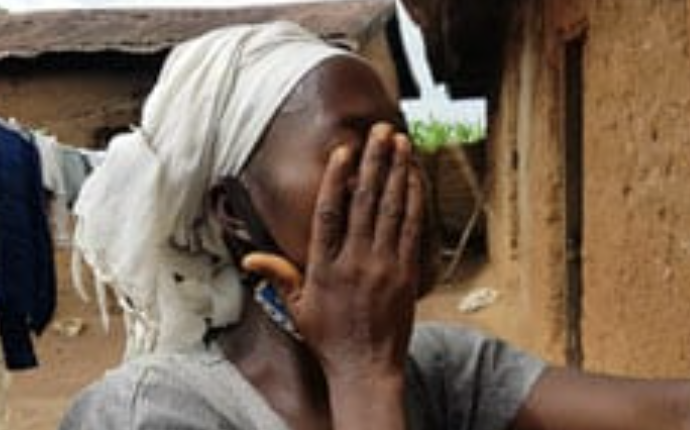 A woman cries against the walls of a mud hut in Nigeria. (Open Doors USA)
