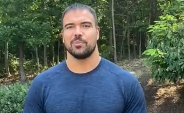 Stefen stands in a backyard with trees and bushes in the background