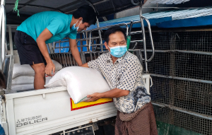Missionaries unload sacks of food from the back of a small truck