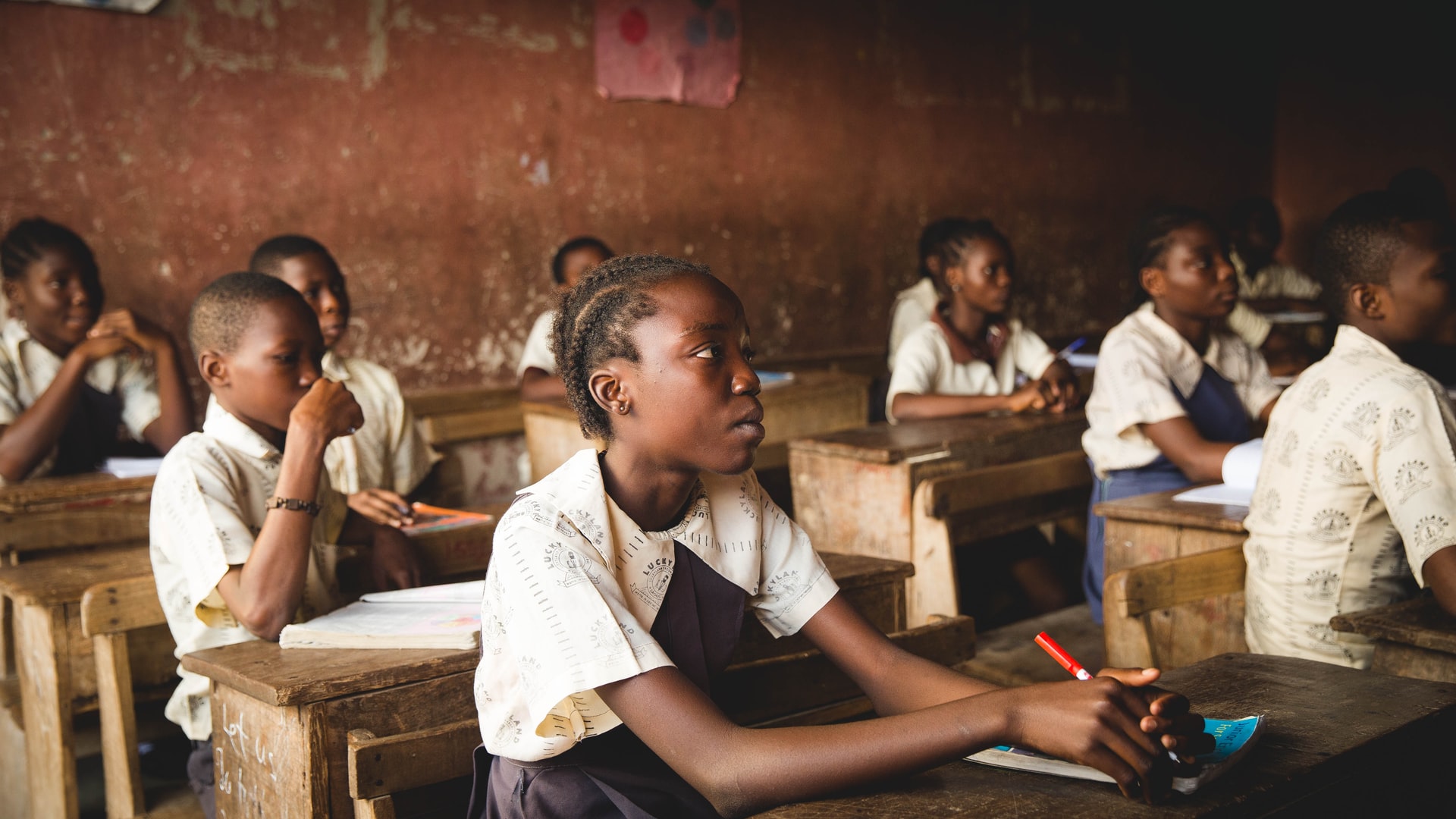 Students sit at desks in a small classroom
