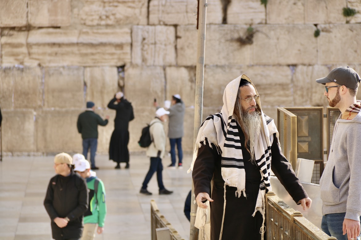 A Jewish man speaks with a tourist with the Wailing Wall in the background.