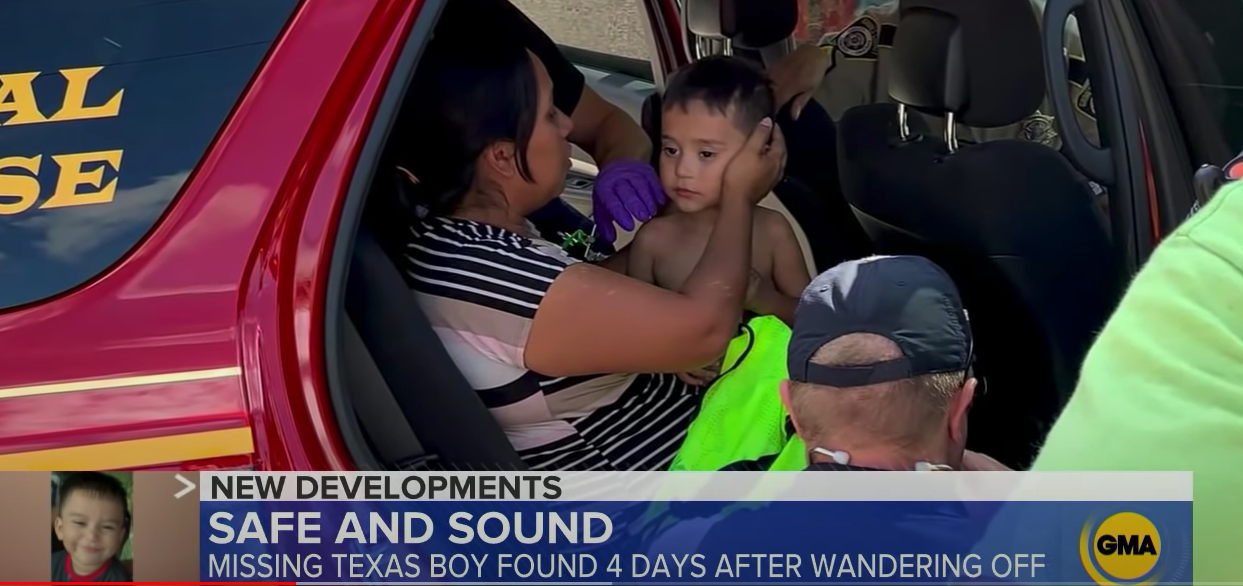 A mother holds a young boy on her lap while sitting in the back of a rescue SUV