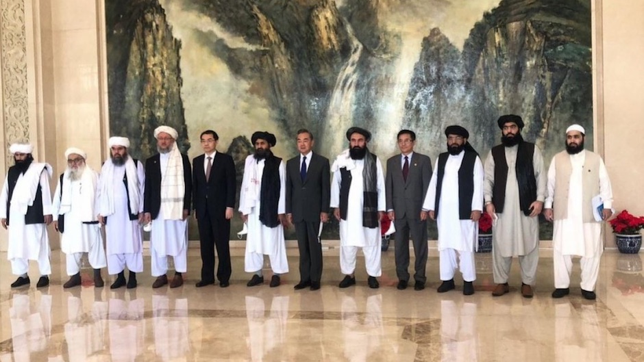 A group of Chinese men in business suits and Taliban officials in traditional Afghan dress stand together