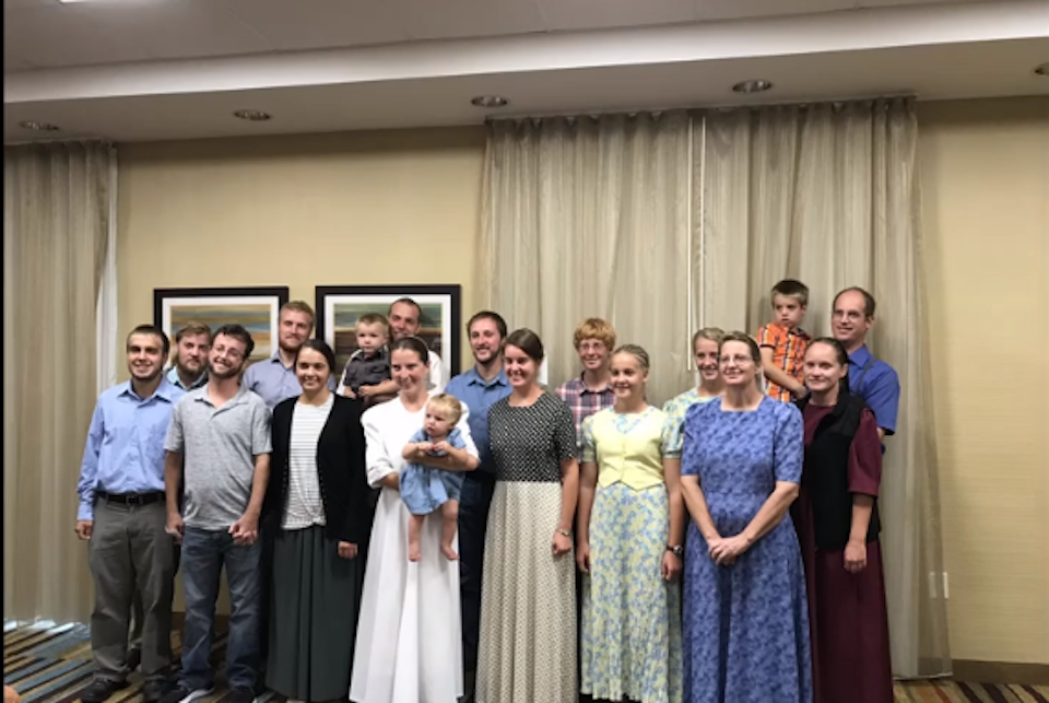 A group of women, men, and children stand smiling for the camera. 