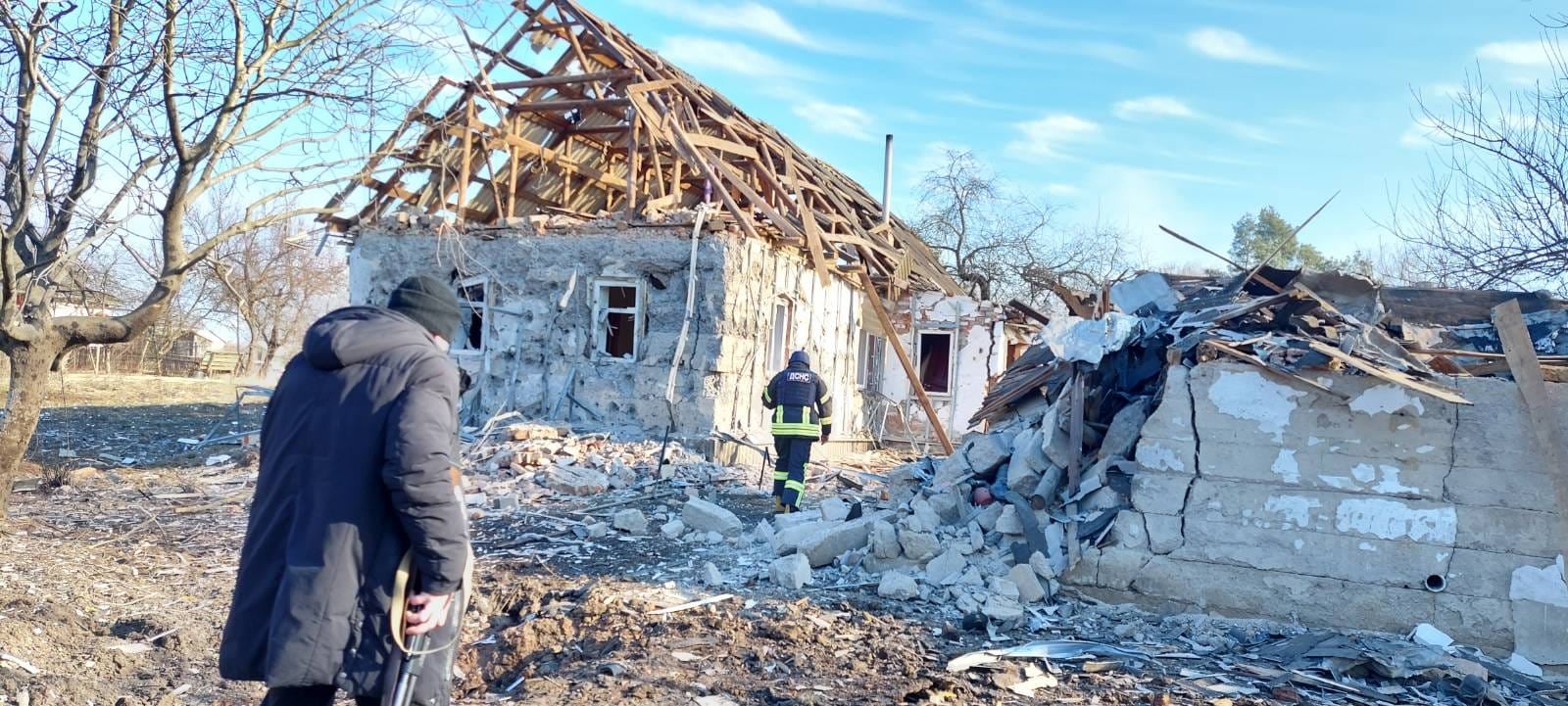 A small building with just wood framing left on its roof and rubble around. 