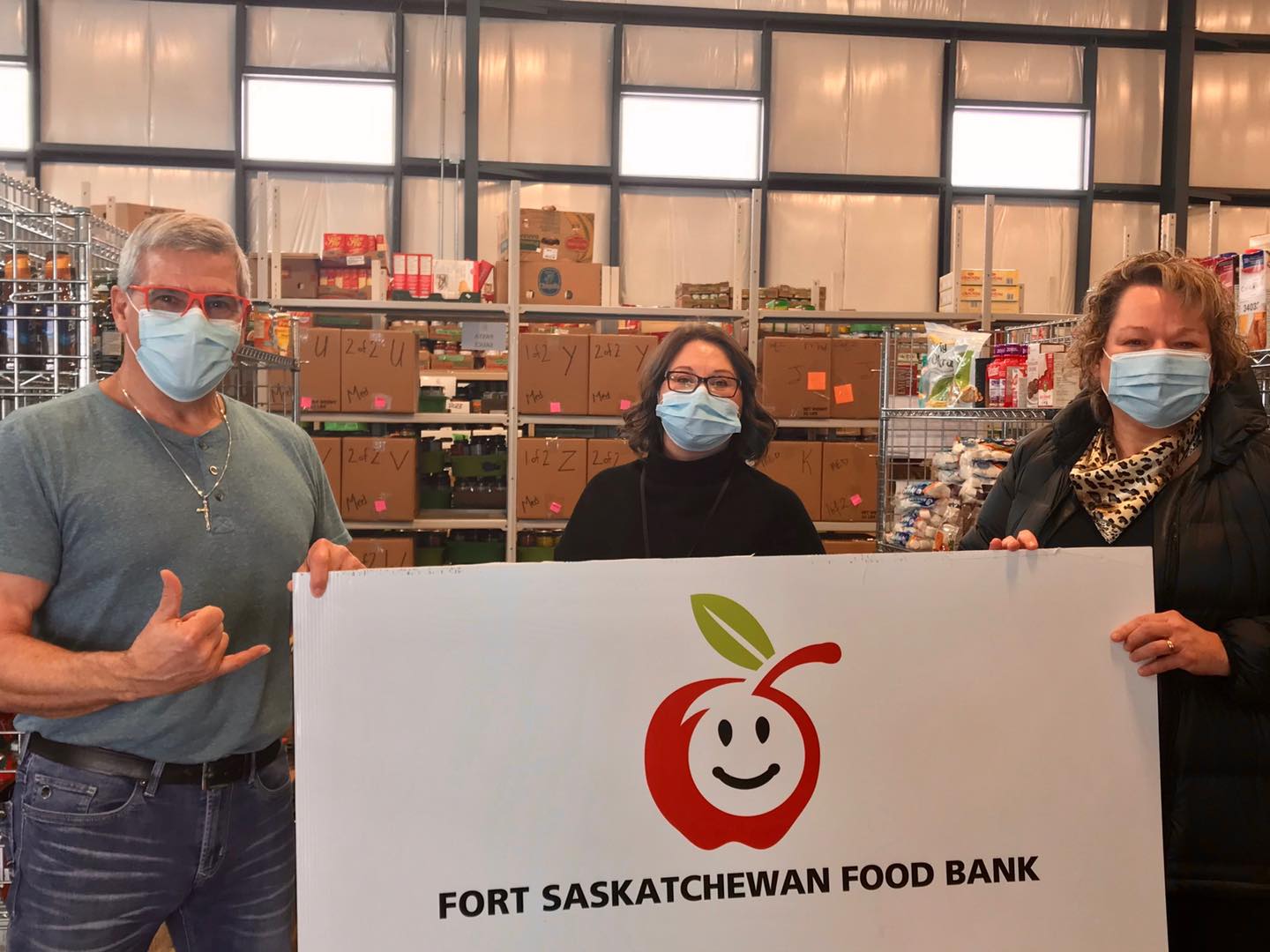 Members of the food bank and the local MLA holding up a Food Bank sign in the food bank's new building.