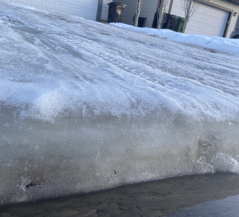 A large slab of ice on a driveway that suddenly drops at the street.