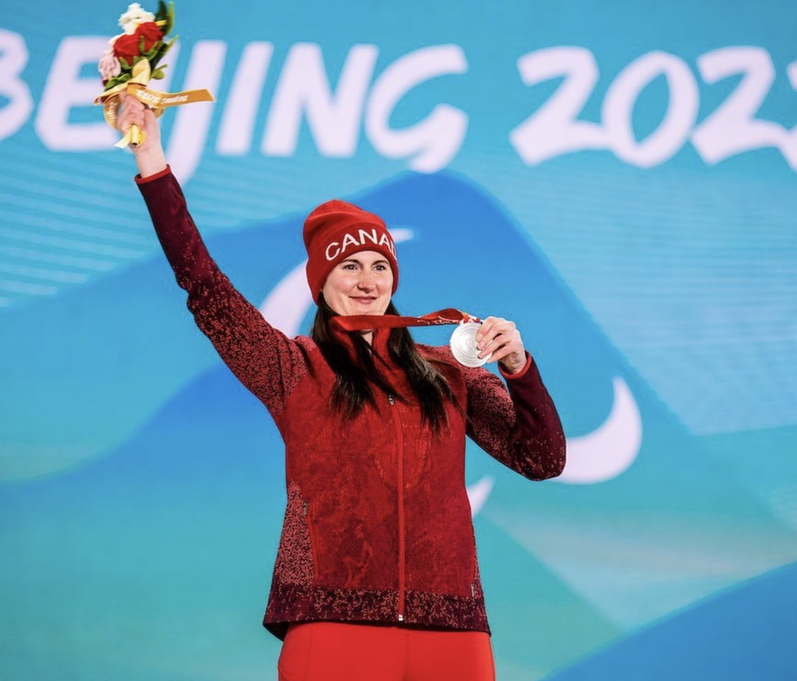 Lisa DeJong hold up her silver medal and flowers.