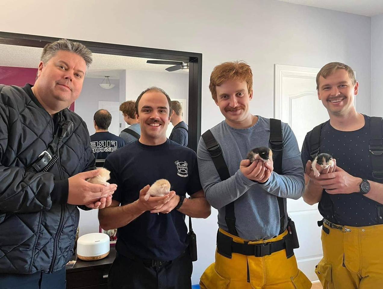 Firefighters holding baby kittens.