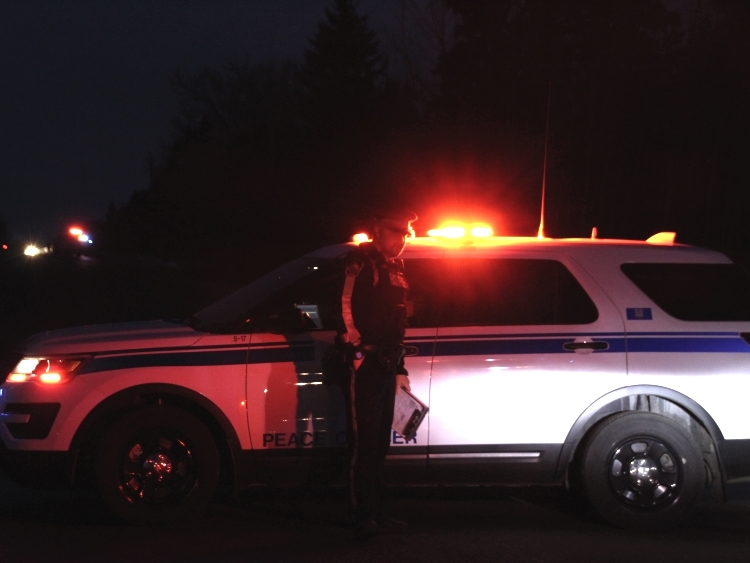 A peace officer in front of his vehicle at night.