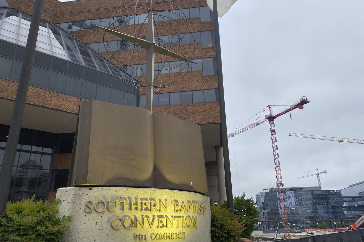 A sign in front of a large building says "Southern Baptist Convention". A crane can be seen in the background of the photo.