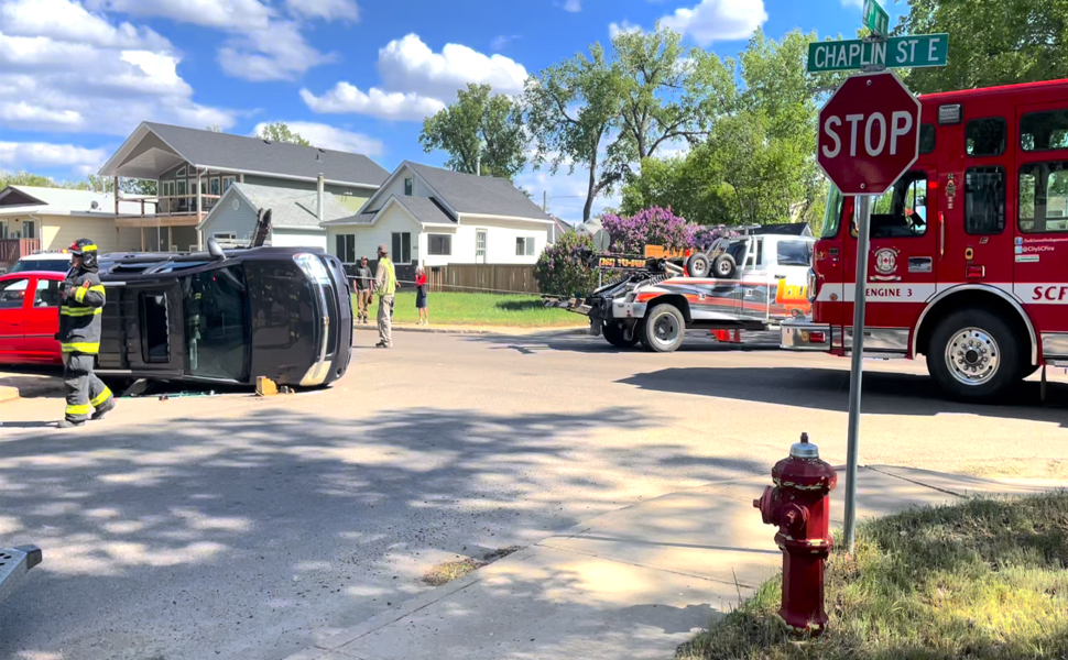 Multiple emergency vehicles and a car on its side.
