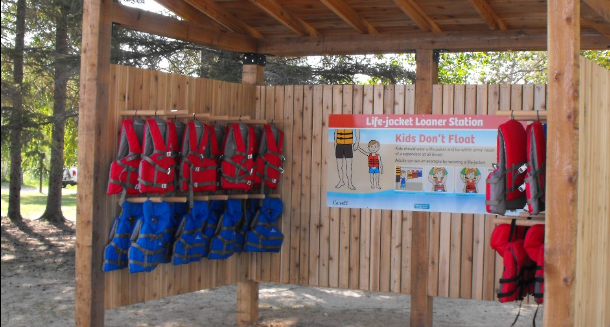 Life jackets hanging in a wooden shelter at a beach.