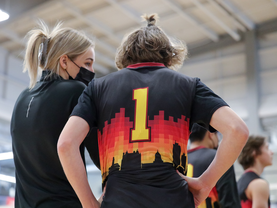 A coach speaks with an athlete in a gymnasium.