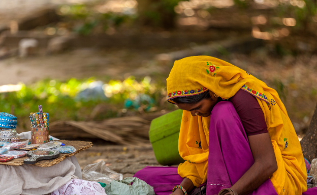 Indian woman sitting on a mat, head down. 