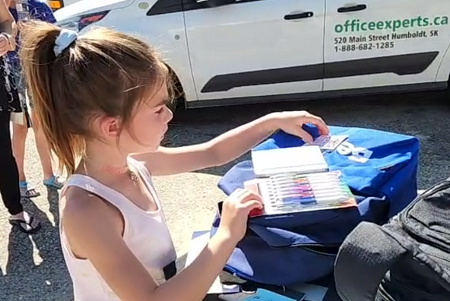 a girl opening a back pack with pens inside