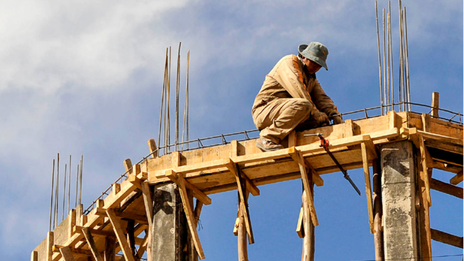 a man sets on top of a concrete form in a building under construction
