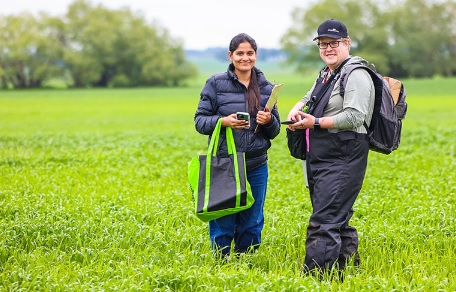 man and woman standing in a field with cell phones