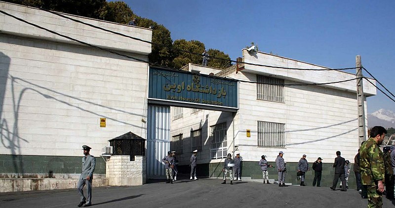 People in uniforms stand outside the entrance to a large white building