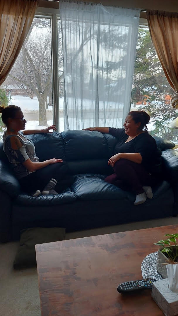 two women sitting on a couch in a living room (Dorothy Penner/Dignity House)