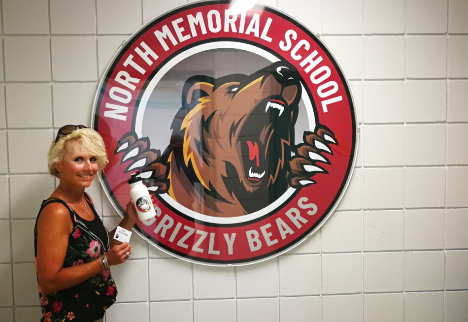 North Memorial School Principal Val Smith in front of the school logo