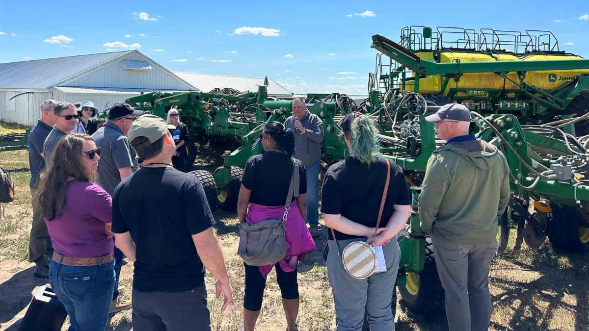 Food influencers visiting with farmer in front of a combine during the tour