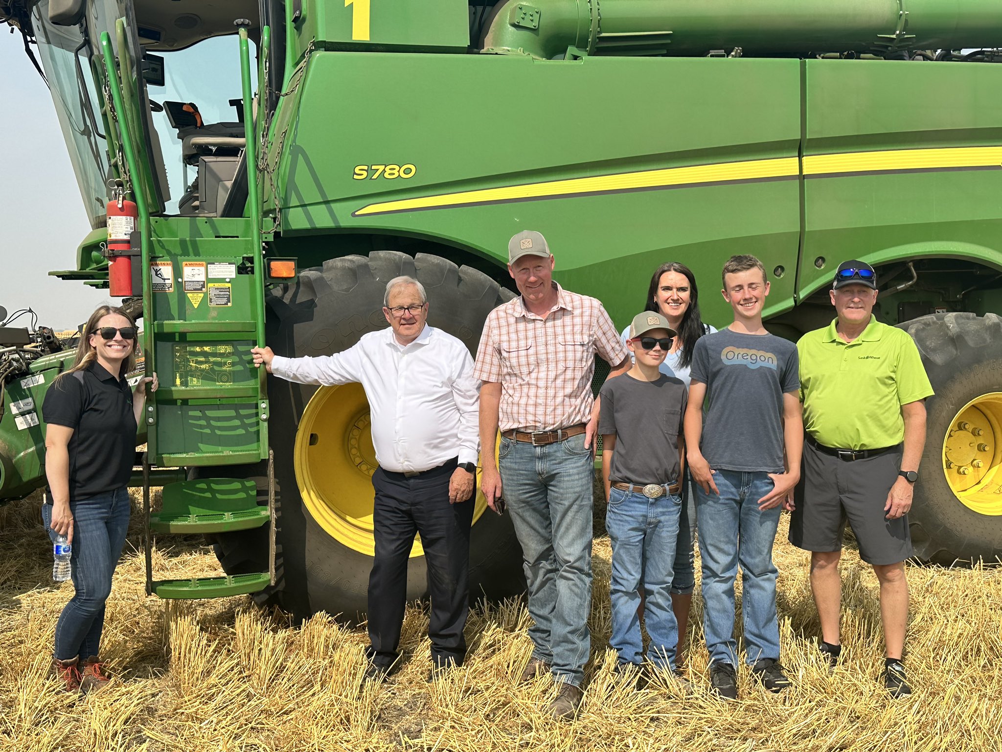 Miniister MacAulay with the Stone family and Sask Wheat officials in front of a John Deere Combine