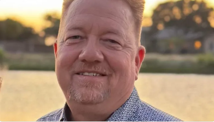 A middle-age man with light skin tone smiles at the camera