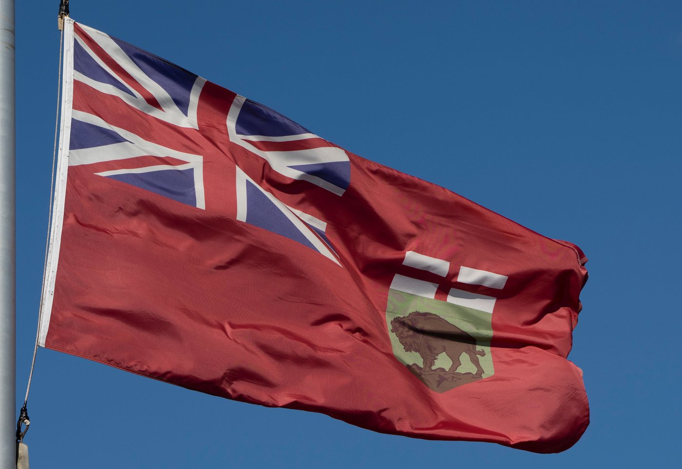 A red flag with a union jack in the upper left corner and a crest with a bison in the lower right corner