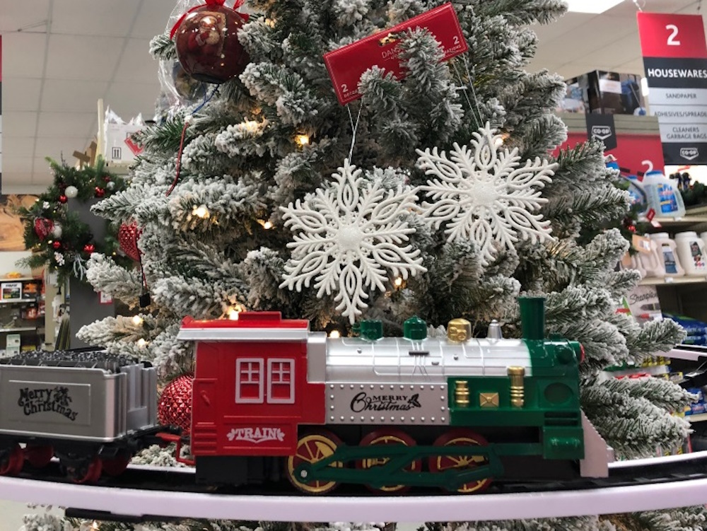 a toy train driving around a Christmas tree