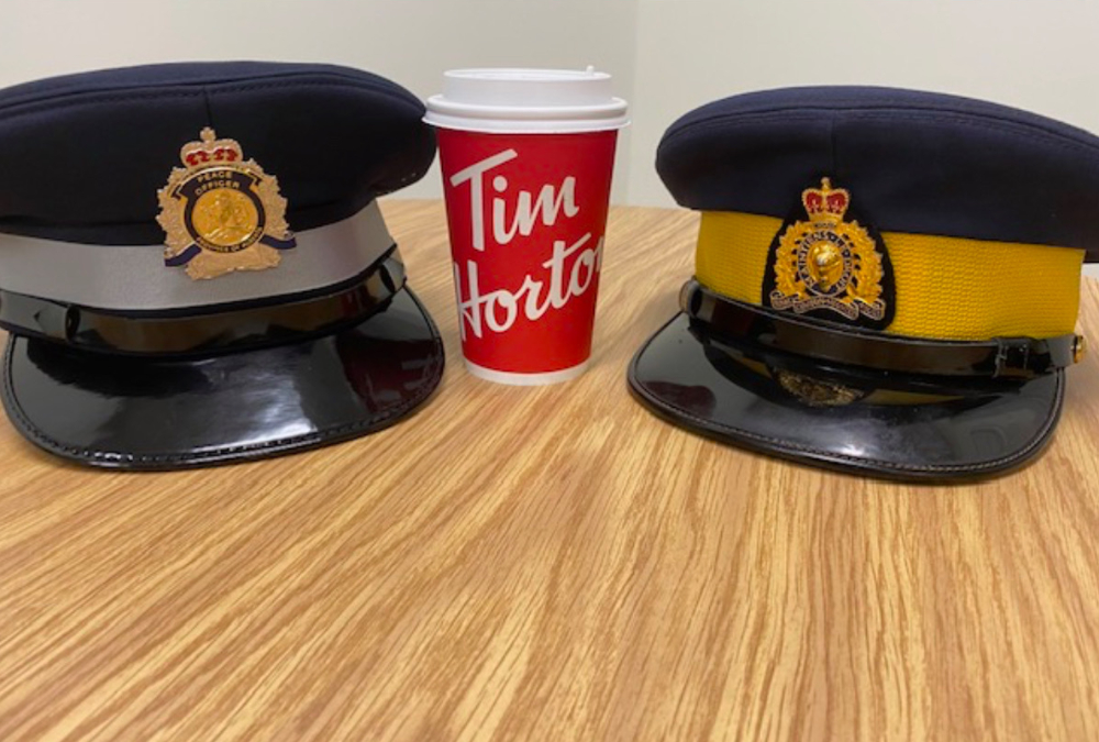 An RCMP hat and a Municipal Enforcement sitting next to a coffee cup.