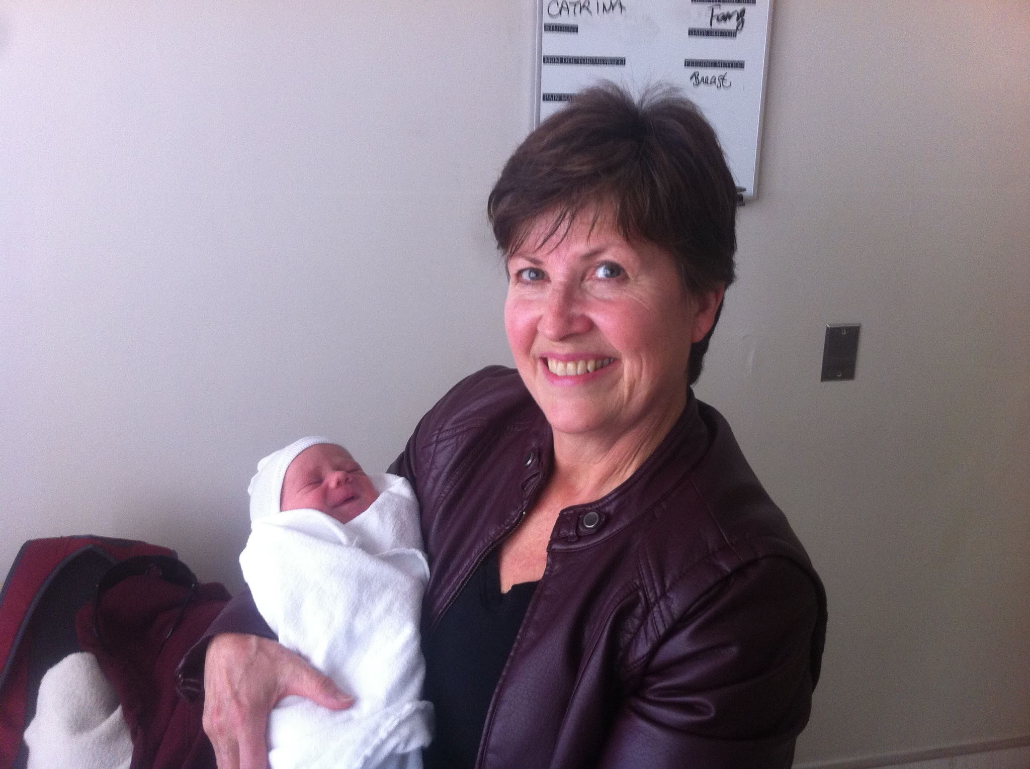 A woman smiles holding a newborn infant