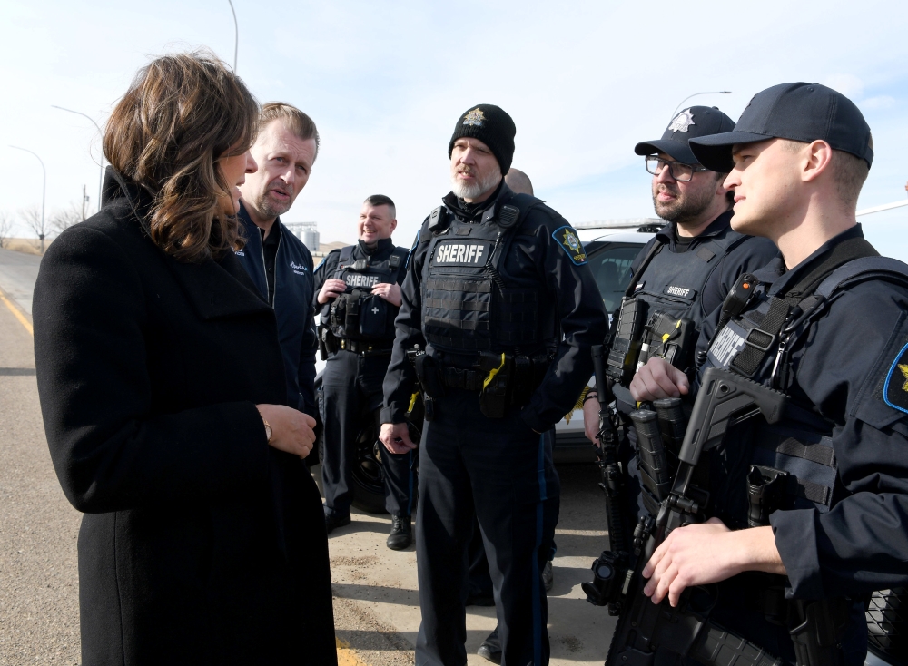 Premier Danielle Smith speaking with several Alberta sheriffs.