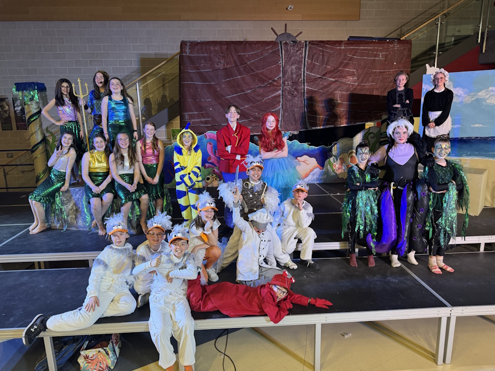Cast of the Little Mermaid stand on stage 