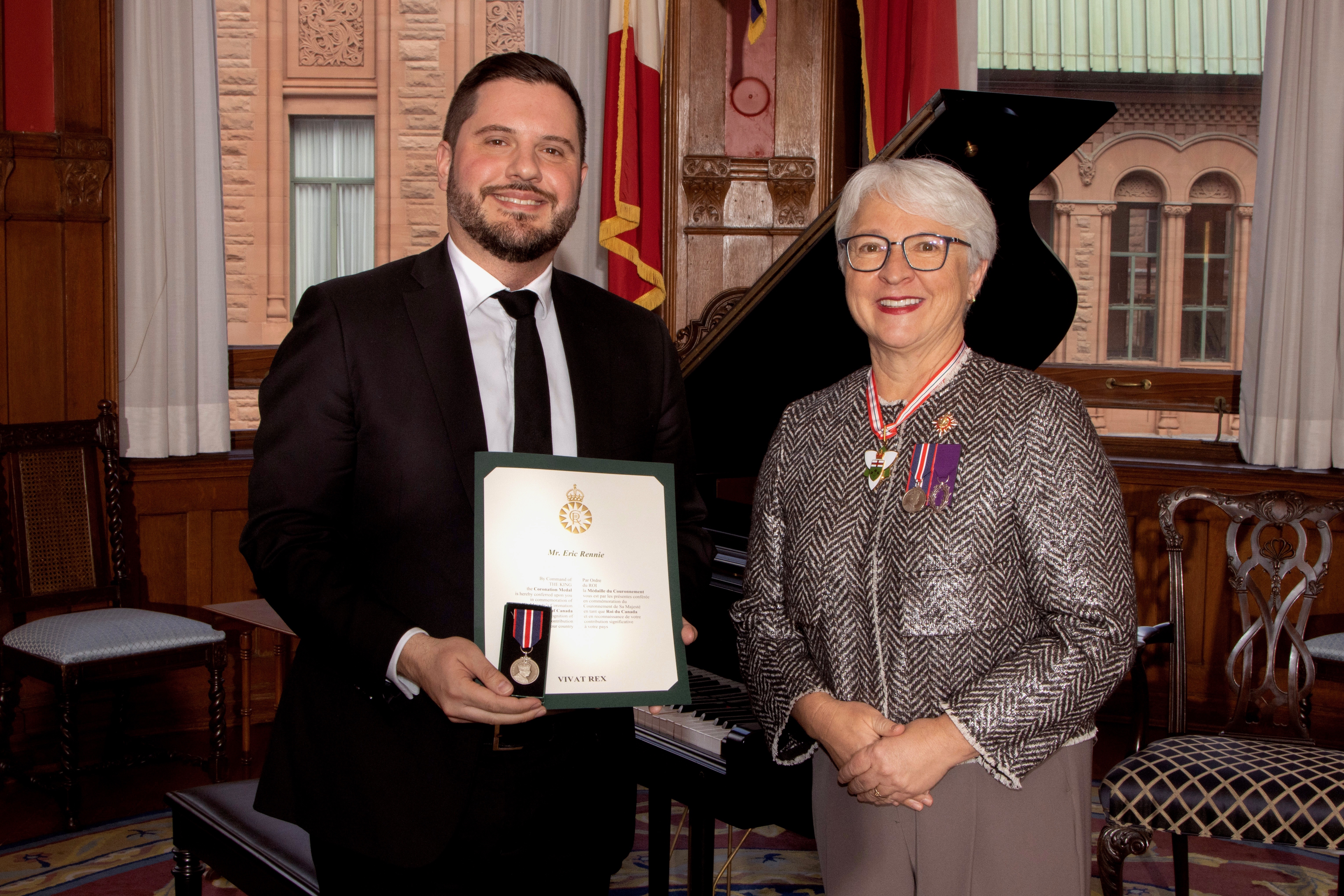 Eric Rennie hold King  Charles III Medal standing with Hon. Edith Dumont, in the LG of Ontario