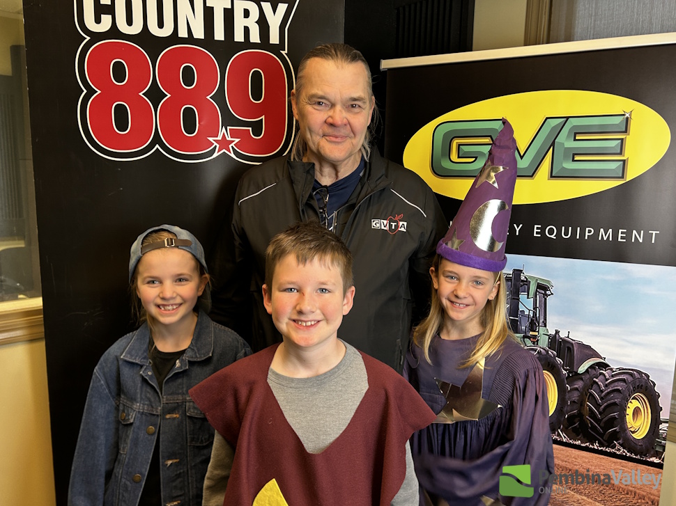 three students in costumes stand with their teacher 