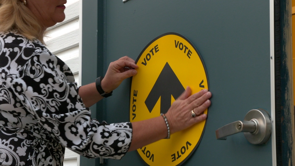 An Elections Canada "VOTE" sign being hung.