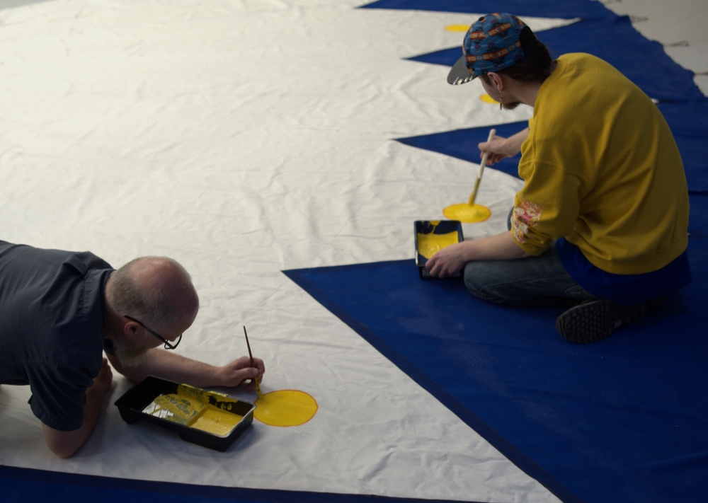 Two people painting the tipi.