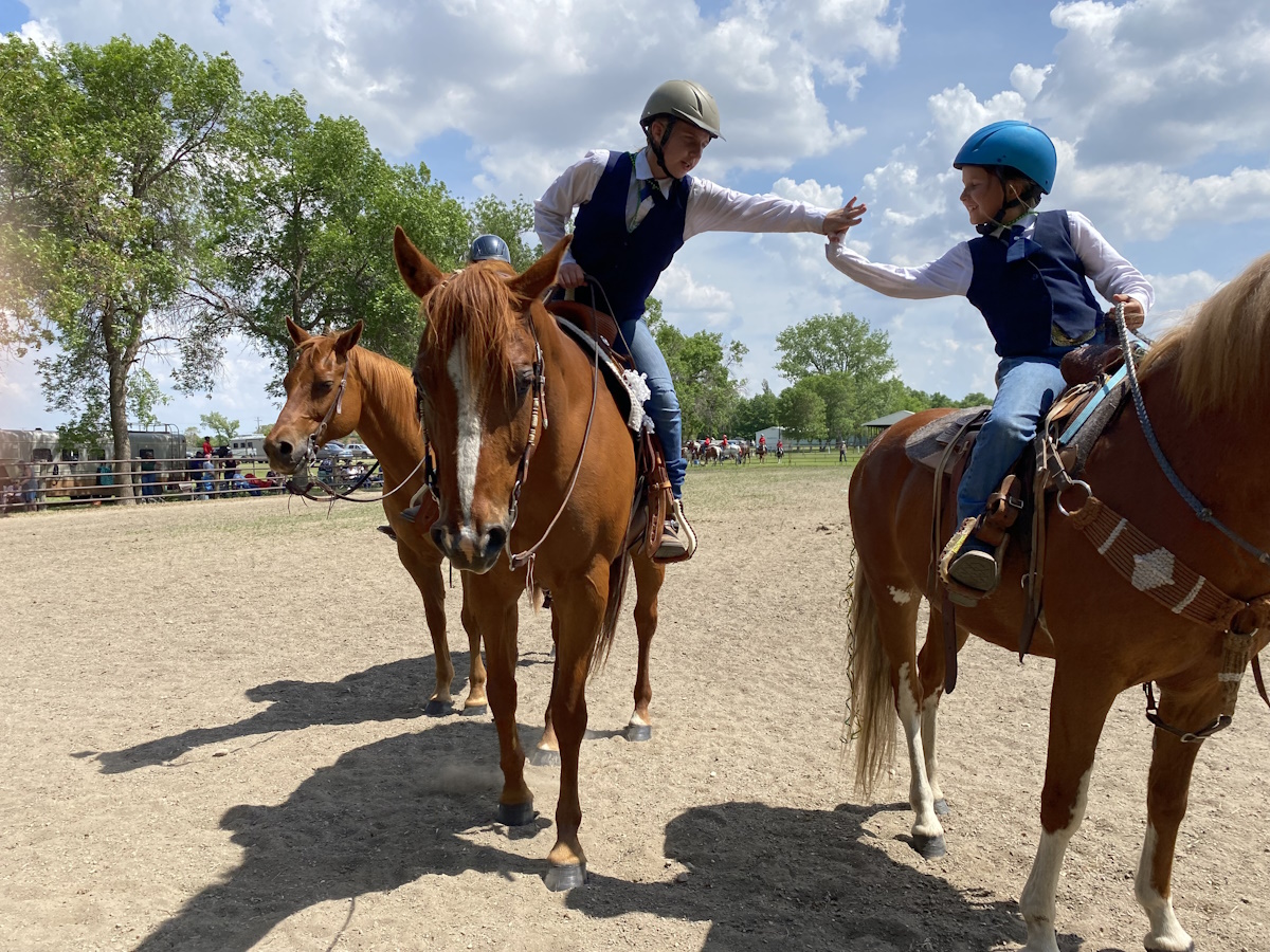 Two horseback riders giving each other a high five