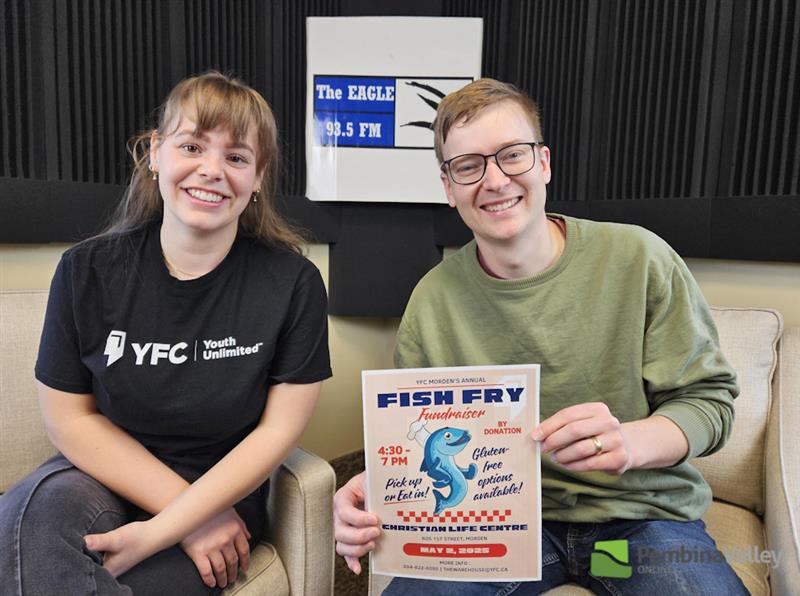 two people sit in a studio displaying a poster
