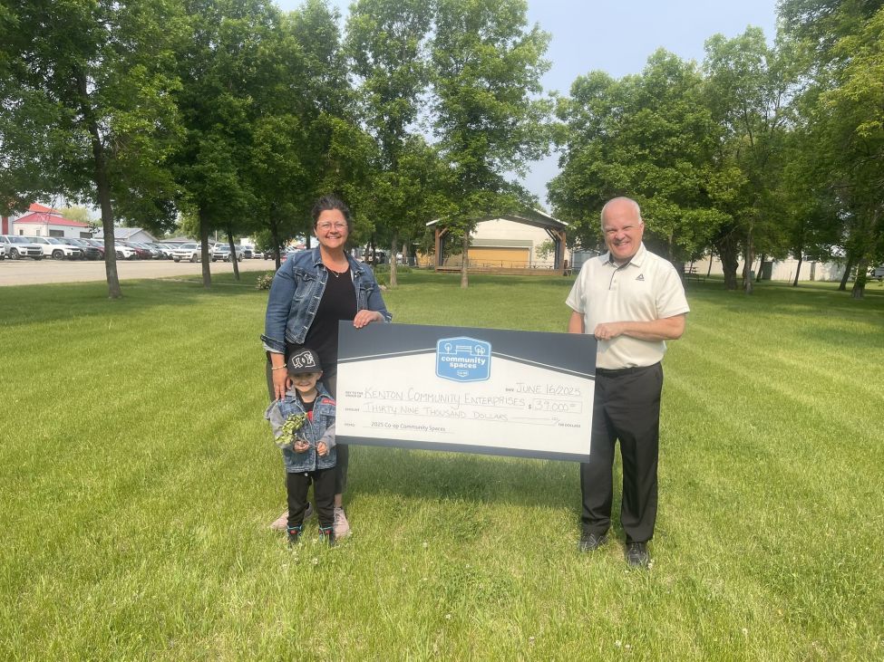 A lady and a man holding a very large cheque in a green space
