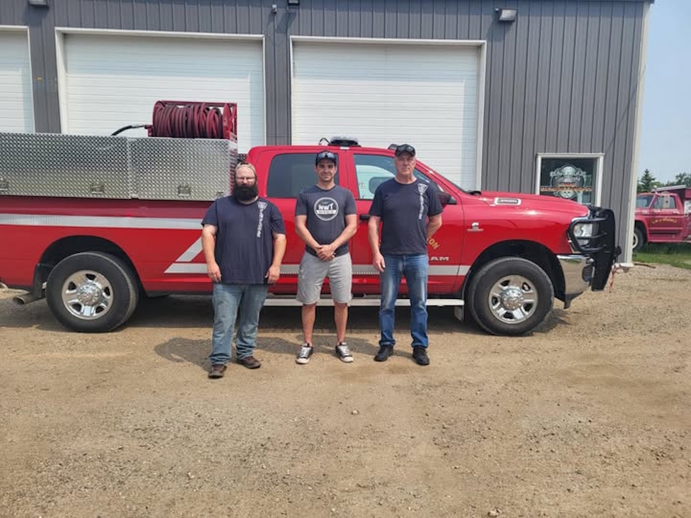 three men standing in front of a fire brush truck