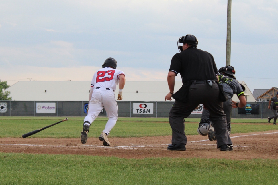 A baseball player in a white uniform running towards first base after an at bat