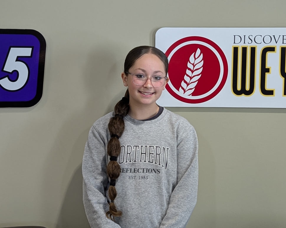 A young girl standing in front of a wall with logos on it