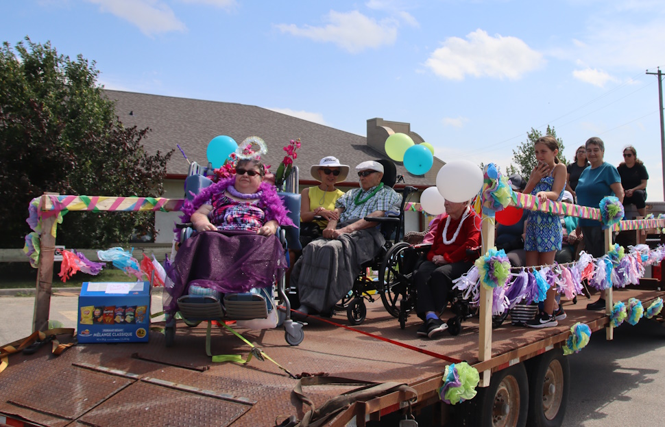 People riding scooters on a trailer for Villa Youville Scooter Parade