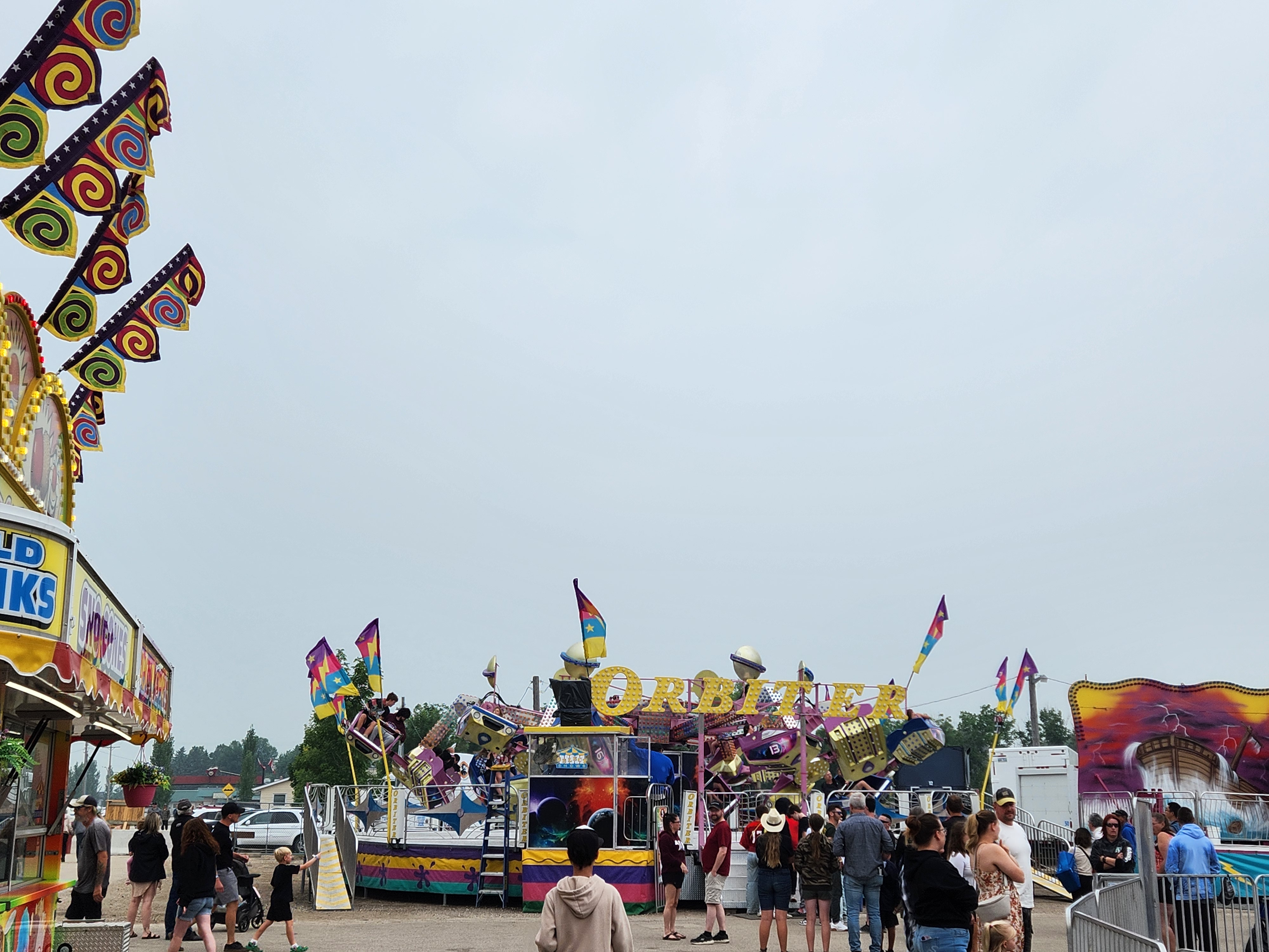 Crowds gather under cloudy skies for a fun-filled afternoon at the Morris Stampede Midway, where colourful rides, carnival games, and family memories take center stage. PortageOnline/ Tristen Sokolosky