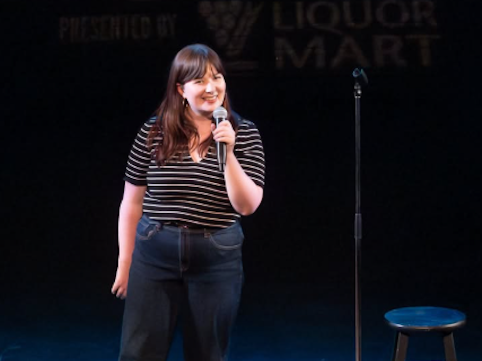 a woman stands on a stage and speaks into a microphone
