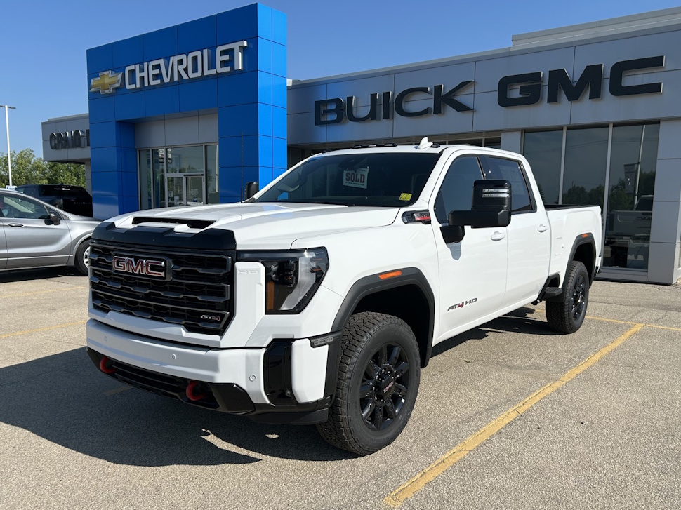 A white pickup truck parked in front of Craig Dunn Motor City dealership building in Portage la Prairie.