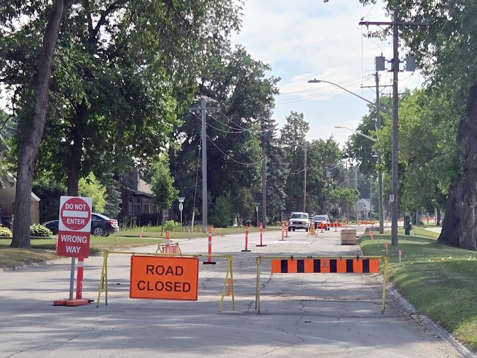 Construction work underway on Crescent Road West in Portage la Prairie, with heavy machinery and road barriers visible during the road closure.