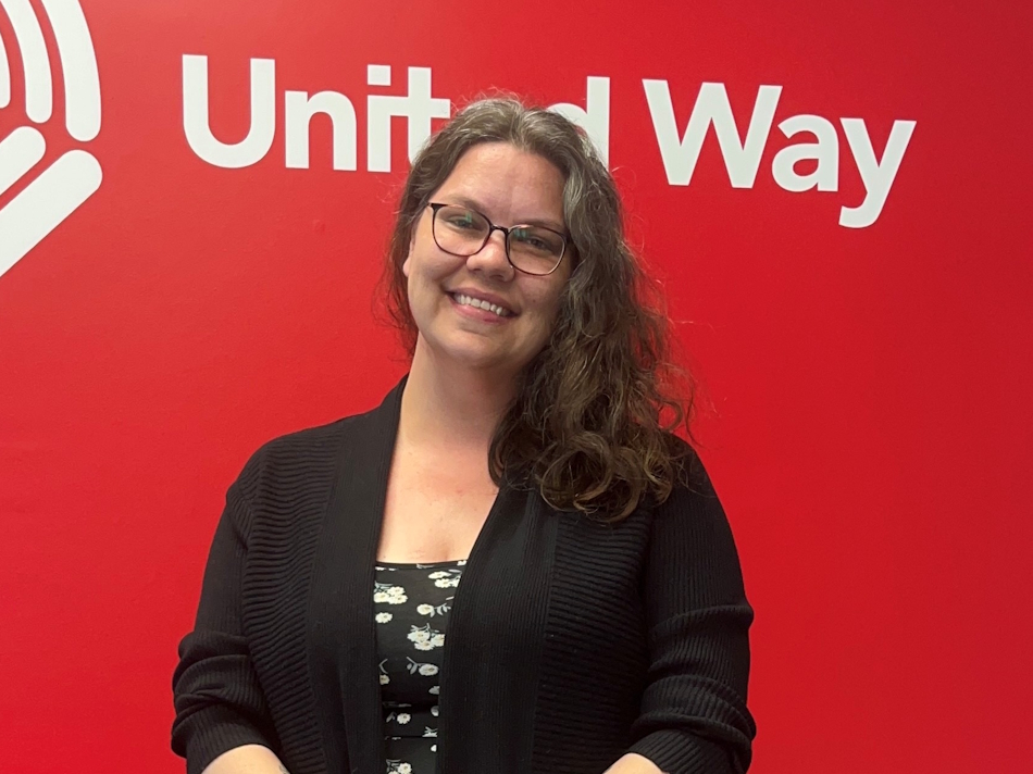 Chelsey Denser standing in front of the United Way red logo wall
